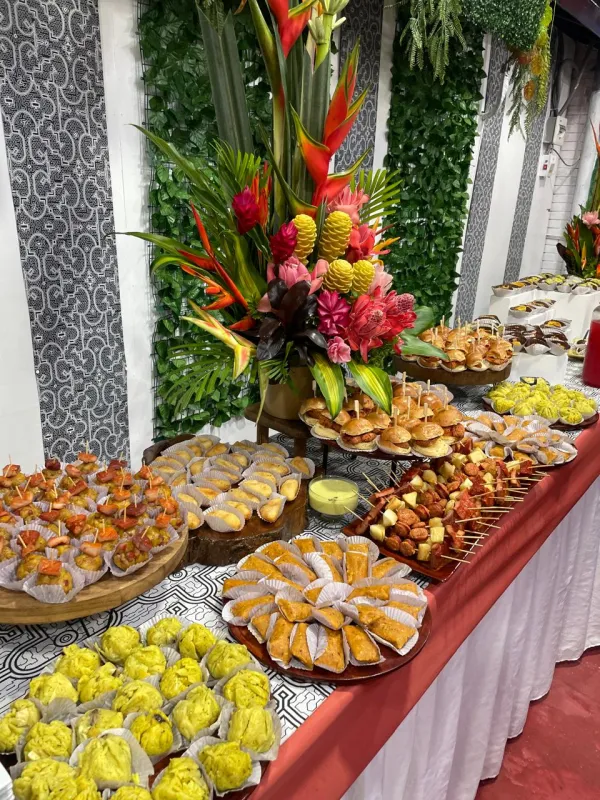 Mesa buffet festiva en un salón de eventos amazónicos, adornada con flores tropicales coloridas para una gran celebración